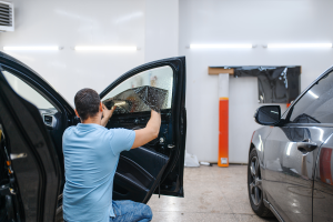 Technician adding tinting to the passenger window in a garage